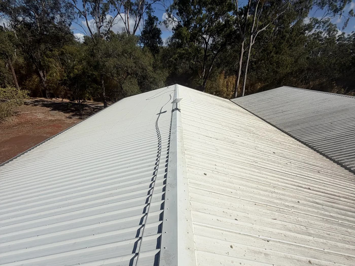Colorbond roof on a rural block in Beecher before a soft wash, gum trees and red dirt behind
